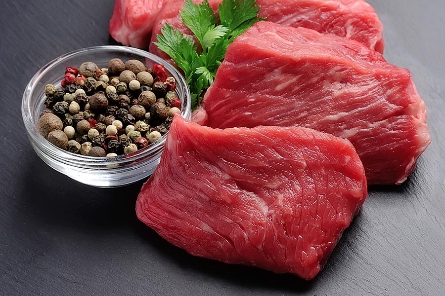 Frisches, rotes Fleisch auf dunklem Stein, mit Gewürzen verziert