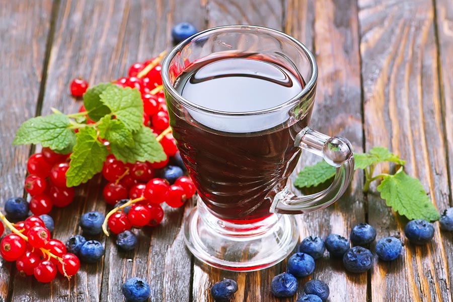 Fruchtsaft in einem Glas auf Holztisch, garniert mit Früchten