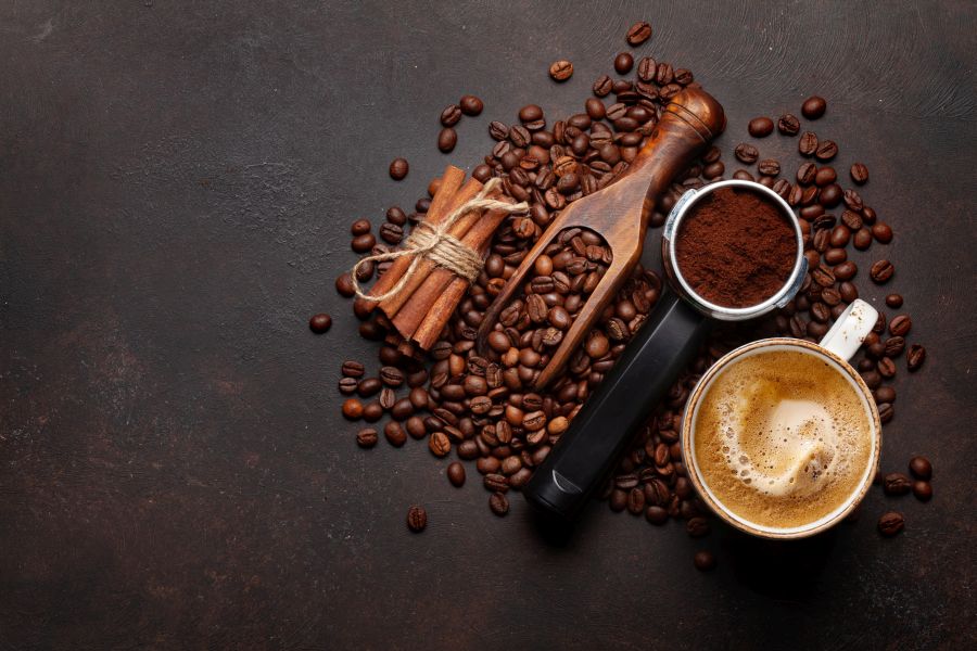 Geröstete Kaffeebohnen neben einer frischen Tasse Kaffee, Ansicht von oben