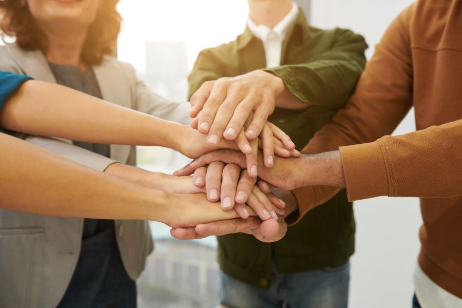 Menschen legen ihre Hände aufeinander als Zeichen von Teamgeist